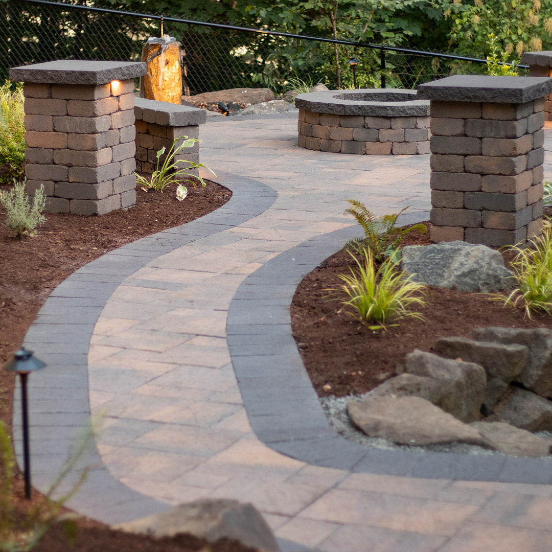 Paved pathway with stone columns and garden features in a backyard setting